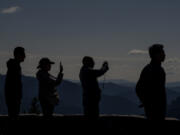 Visitors take photos at Sunrise Point, with the Cascade Range in the background, Thursday, Sept. 21, 2023, at Mount Rainier National Park, near Sunrise, Wash.