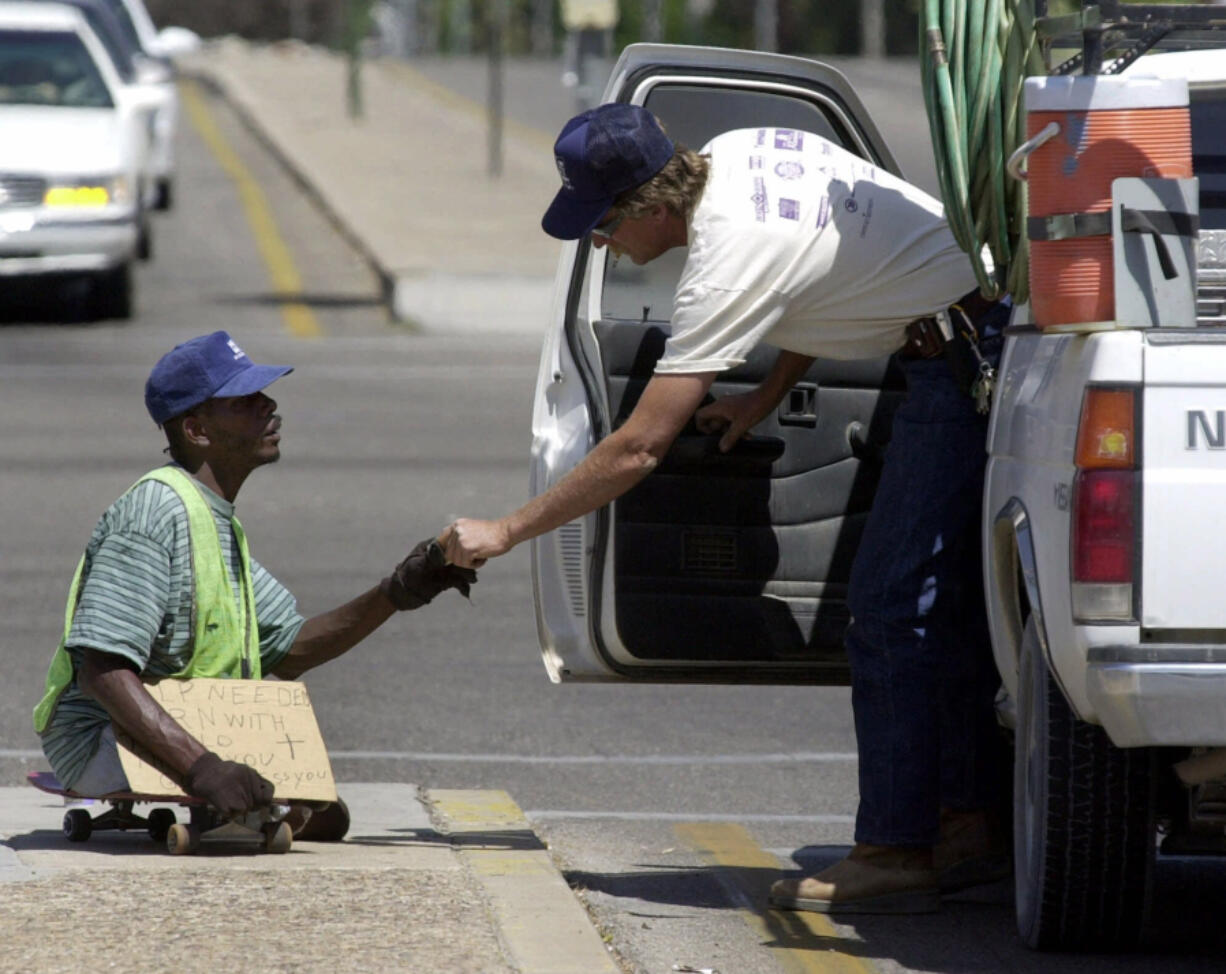 A man accepts money from a passing motorist in Tucson, Ariz.