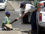 A man accepts money from a passing motorist in Tucson, Ariz.