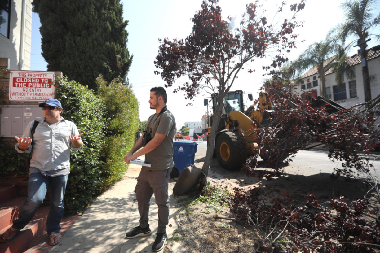 California State, Los Angeles, professor Eric Wood, left, and former CSLA student Christian Benitez take a break from searching for birds in Los Angeles, as a public works crew collects tree branches and leaves. Trees losing their limbs is typically associated with severe weather such as tornadoes, hurricanes and thunderstorms. But a little known risk outside of arborist circles is that mature and seemingly healthy trees can suddenly lose branches in summer weather.