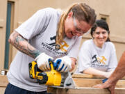 Nichole Mosley, an inmate at the Athens-Clarke County Jail, smiles as she saws through a piece of wood while building a tiny home in the jail yard in Athens, Georgia, on July 27, 2024.