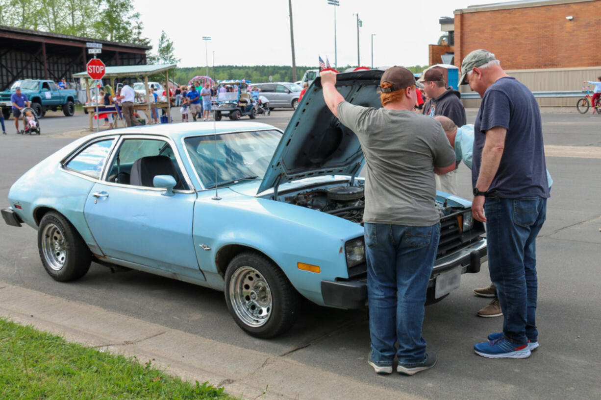 Minnesotans talk vintage cars with the governor, right, over the engine of a 1978 Ford Pinto in 2022.