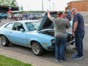 Minnesotans talk vintage cars with the governor, right, over the engine of a 1978 Ford Pinto in 2022.