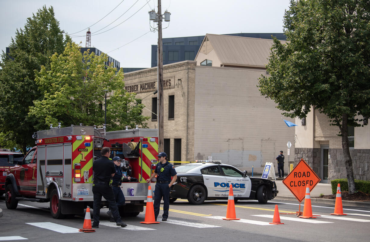 Vancouver Fire Department firefighters stand behind orange cones that block a section of Columbia Street on Friday, Aug. 9, 2024, in Vancouver. Police closed streets near Columbia at Phil Arnold Way in downtown Vancouver around 11 a.m. due to a bomb threat.