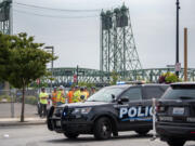 Construction workers stand near Vancouver Police vehicles Friday, Aug. 9, 2024, after being evacuated from their work sites due to a bomb threat in downtown Vancouver.