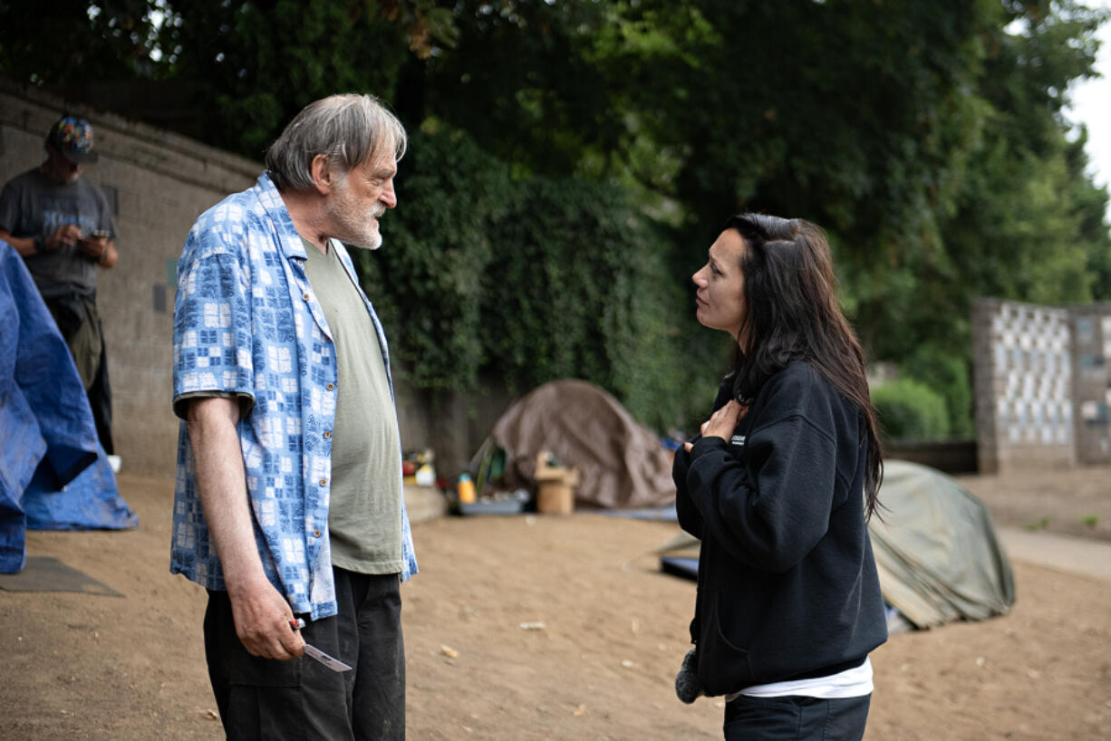 Camper Bradley Torson of Vancouver talks with Tiffini Dillard from the city of Vancouver&rsquo;s Homelessness Assistance and Resource Team as she offers support during a solid waste sweep along the Mill Plain Boulevard sound wall.