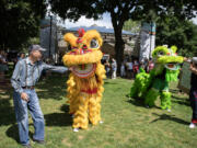 Vancouver resident Tom Nguyen, left, &ldquo;feeds&rdquo; a lion from the Vietnamese Community of Clark County on Friday during the Vancouver USA Arts &amp; Music Festival at Esther Short Park.