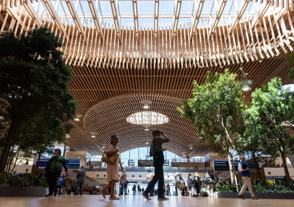 Travelers walk underneath the Pacific Northwest-sourced mass timber roof of Portland International Airport&rsquo;s new main terminal on Wednesday. Opening the new main terminal to the public marked the end of Phase 1 of the PDX Next project, with Phase 2 and the completion of all construction scheduled to wrap up in early 2026.