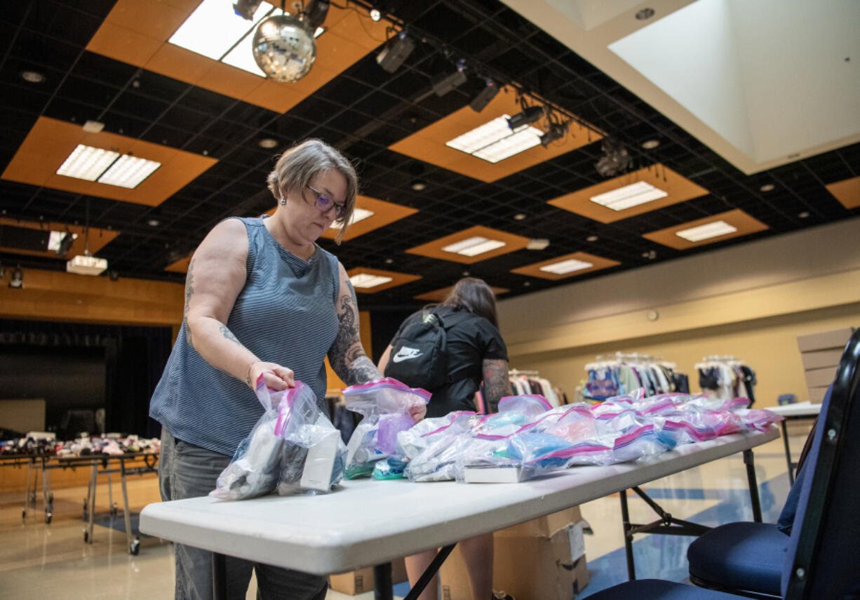 Volunteers Morgan May, left, and Jessica Erick place bags of hygienic items on a table Thursday during a Treehouse pop-up shop at Clark College. The nonprofit event was set up for foster youth to pick out backpacks, new clothes and school supplies in person before the new school year begins.