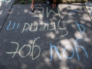 An intern writes a positive message in chalk outside the Clark County Juvenile Justice Center in Vancouver on Tuesday afternoon. .