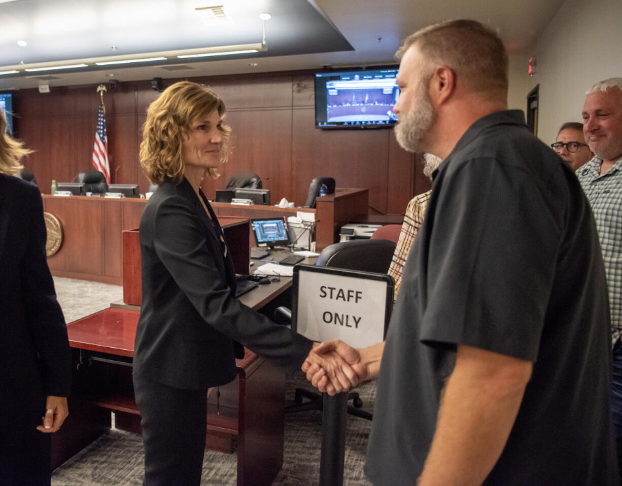 Newly sworn-in Battle Ground City Manager Kris Swanson, left, shakes hands with council member Eric Overholser on Monday during a Battle Ground City Council meeting at Battle Ground City Hall.