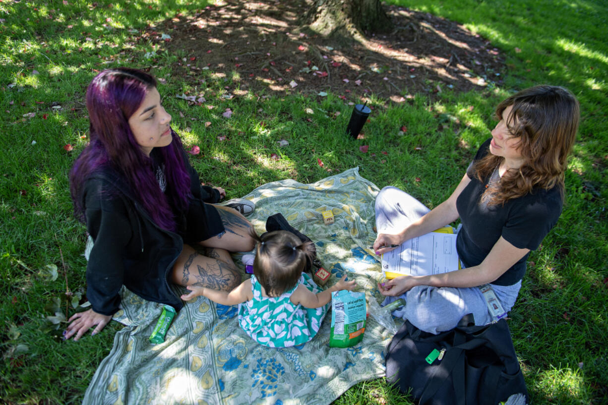 Isabella Lippelgoos of Vancouver, from left, joins her daughter, Rosemary Luna, 14 months, as they work with Clark County nurse Ariel Magram during a visit at Jaggy Road Park on Monday afternoon. Clark County Public Health&rsquo;s Nurse-Family Partnership assists low-income moms from pregnancy until their child&rsquo;s second birthday.