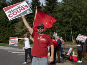 Washington State University fan Will Fisher, left, joins his dad, P.J. Fisher, who is a member of the class of 2003, and other supporters while greeting students on the first day of classes at Washington State University Vancouver on Monday morning.