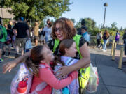 Second-grader Avery Harrington, 7, left, and her sister, third-grader Addison Harrington, 8, in purple, get a warm welcome from bilingual staff member Maria Vasquez, yellow vest, while arriving on the first day of school at Sarah J. Anderson Elementary School on Wednesday morning.