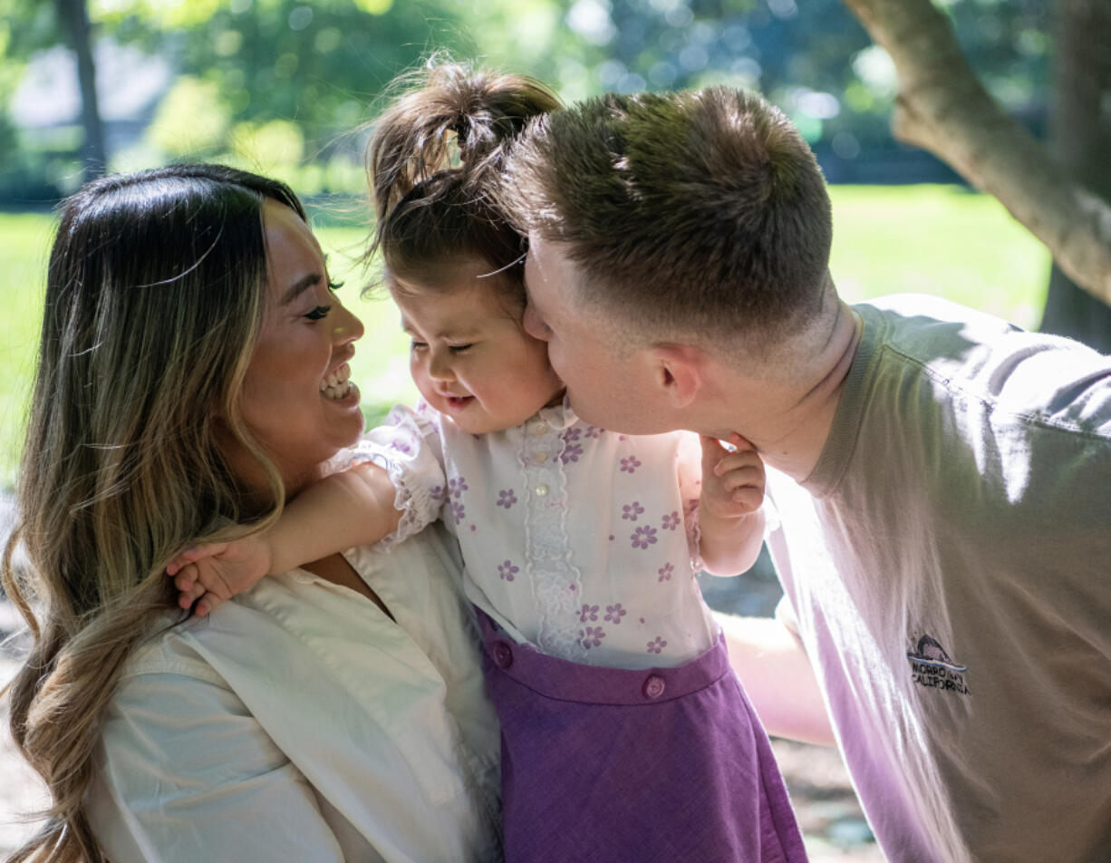 Trent Standard, right, kisses his daughter Hazel, 2, on the cheek while mom Janet holds her Friday at Homestead Park in east Vancouver. The Standards are hosting a Walk-A-Thon fundraiser Saturday at Evergreen High School to raise money for their daughter who has a rare condition called Smith-Magenis syndrome.