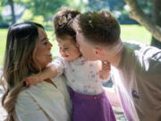 Trent Standard, right, kisses his daughter Hazel, 2, on the cheek while mom Janet holds her Friday at Homestead Park in east Vancouver. The Standards are hosting a Walk-A-Thon fundraiser Saturday at Evergreen High School to raise money for their daughter who has a rare condition called Smith-Magenis syndrome.