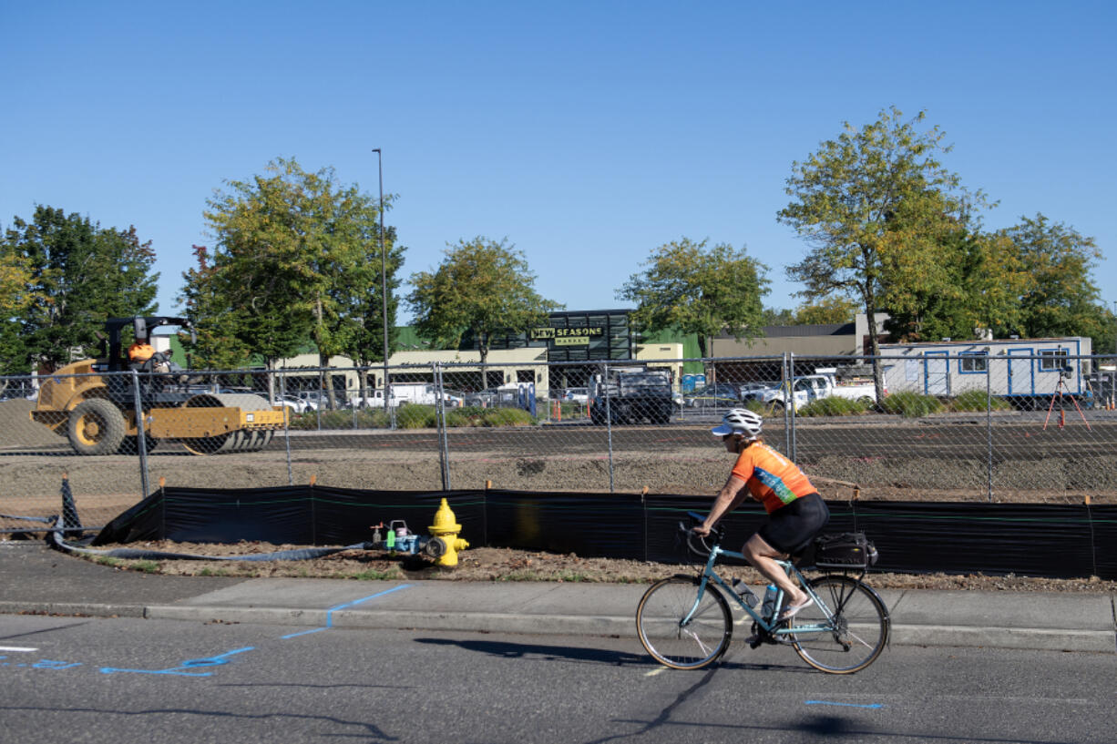 A cyclist passes construction crews as they make way for a new building to house Shake Shack and Starbucks at Fisher&rsquo;s Landing Marketplace. Daiso is also expected to open at the shopping center later this year.