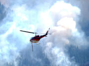 Helicopter heads toward a ridge to make a water drop on a wildland fire burning near the Ken Caryl Ranch development Wednesday, July 31, 2024, southwest of Littleton, Colo.