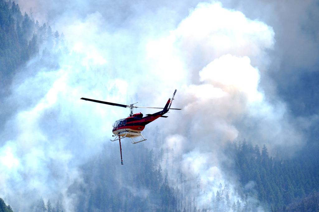 Helicopter heads toward a ridge to make a water drop on a wildland fire burning near the Ken Caryl Ranch development Wednesday, July 31, 2024, southwest of Littleton, Colo.