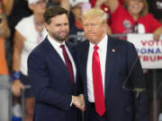 Republican vice presidential candidate Sen. JD Vance, R-Ohio, left, and Republican presidential candidate former President Donald Trump, shake hands at a campaign rally at Georgia State University in Atlanta, Saturday, Aug.