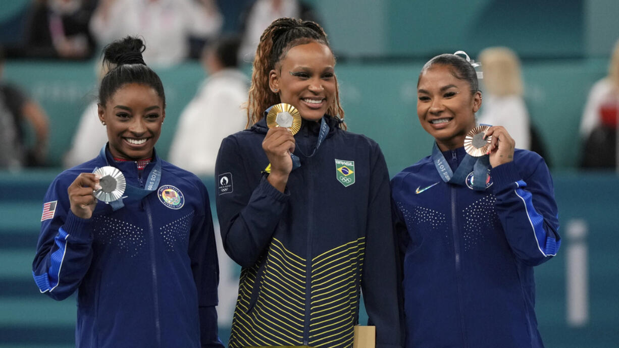 Gold medalist Rebeca Andrade, center, of Brazil, celebrates on the podium with silver medalist Simone Biles, left, of the United States, and Jordan Chiles, also of the United States, during medal ceremony for the women's artistic gymnastics individual floor finals at Bercy Arena at the 2024 Summer Olympics, Monday, Aug. 5, 2024, in Paris, France.