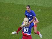 Mallory Swanson, of the United States, up, celebrates with Lindsey Horan, of the United States, after scoring her side's first goal during the women's soccer gold medal match between Brazil and the United States at the Parc des Princes during the 2024 Summer Olympics, Saturday, Aug. 10, 2024, in Paris, France.