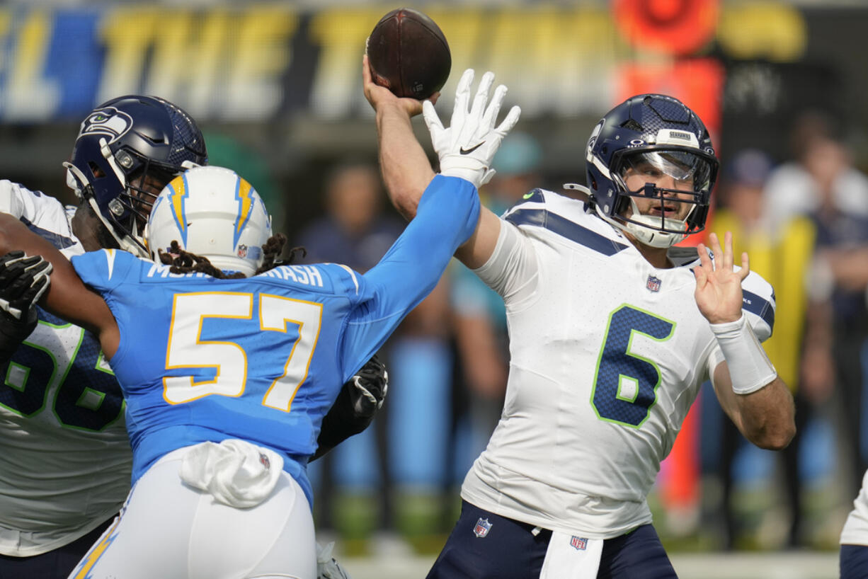 Seattle Seahawks quarterback Sam Howell (6) passes as Los Angeles Chargers linebacker Tre'Mon Morris-Brash (57) applies pressure during the first half of a preseason NFL football game in Inglewood, Calif., Saturday, Aug. 10, 2024.