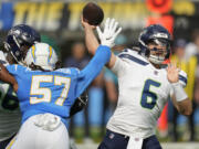 Seattle Seahawks quarterback Sam Howell (6) passes as Los Angeles Chargers linebacker Tre'Mon Morris-Brash (57) applies pressure during the first half of a preseason NFL football game in Inglewood, Calif., Saturday, Aug. 10, 2024.