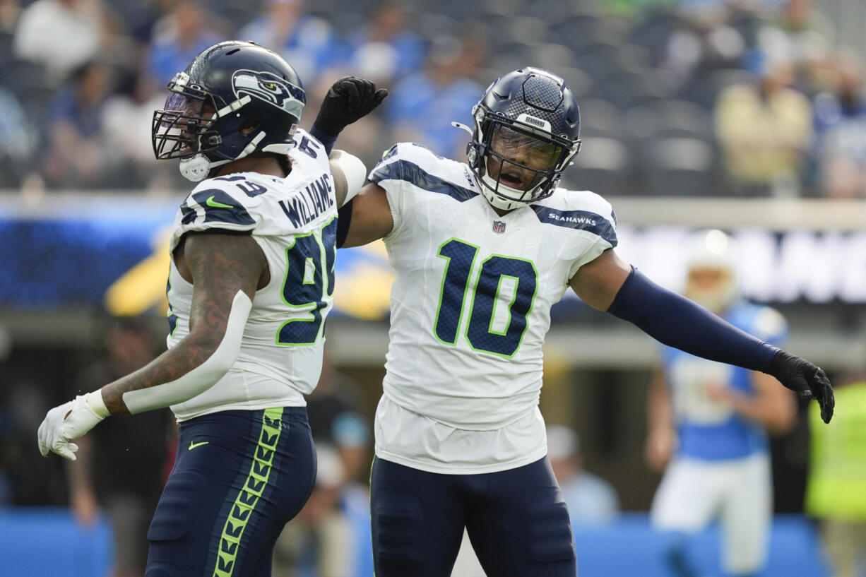 Seattle Seahawks defensive end Leonard Williams (99) reacts with linebacker Uchenna Nwosu (10) during the first half of a preseason NFL football game against the Los Angeles Chargers in Inglewood, Calif., Saturday, Aug. 10, 2024.