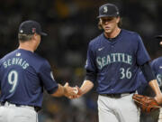 Seattle Mariners starting pitcher Logan Gilbert (36) hands the ball to manager Scott Servais, left, during the seventh inning of a baseball game against the Pittsburgh Pirates, Friday, Aug. 16, 2024, in Pittsburgh.