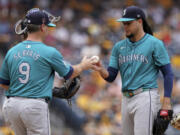 Seattle Mariners starting pitcher Luis Castillo, right, hands the ball to manager Scott Servais, left, during the sixth inning of a baseball game against the Pittsburgh Pirates, Saturday, Aug. 17, 2024, in Pittsburgh.