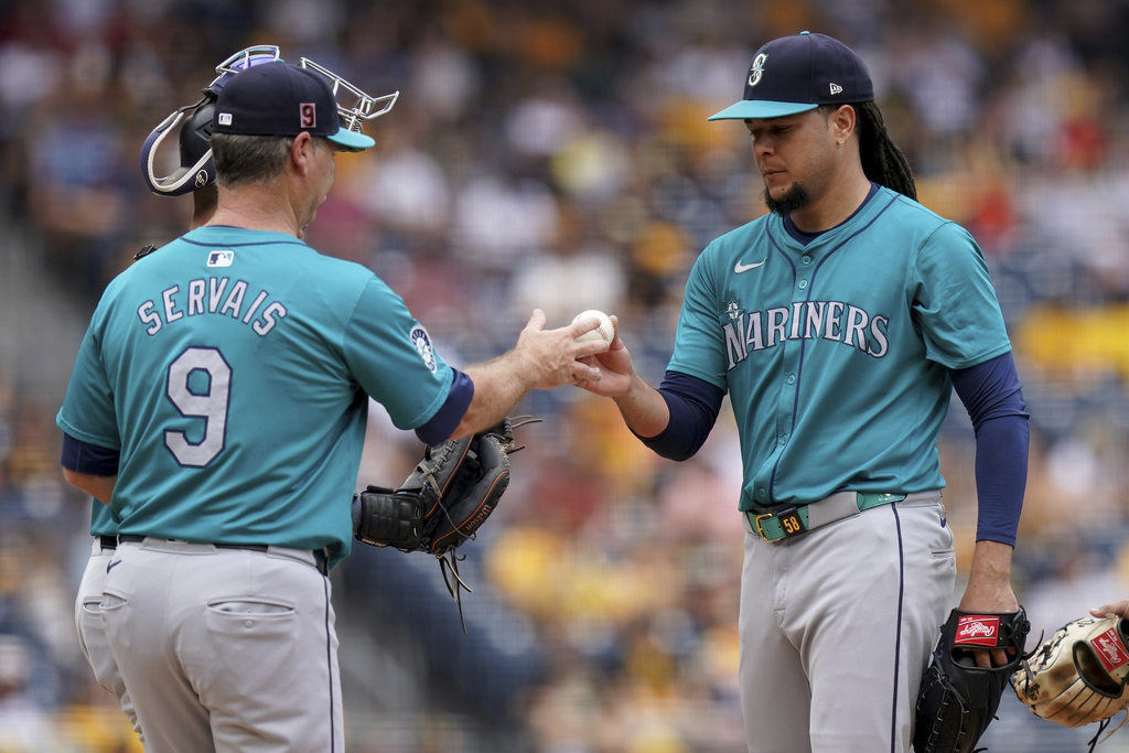 Seattle Mariners starting pitcher Luis Castillo, right, hands the ball to manager Scott Servais, left, during the sixth inning of a baseball game against the Pittsburgh Pirates, Saturday, Aug. 17, 2024, in Pittsburgh.