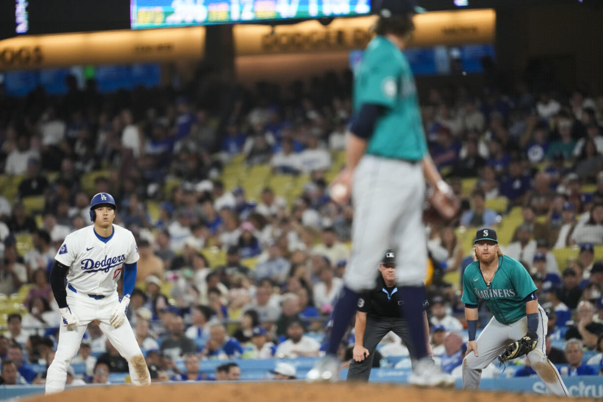 Los Angeles Dodgers designated hitter Shohei Ohtani (17) leads off of first as Seattle Mariners starting pitcher Logan Gilbert, center, looks back to first baseman Justin Turner, right, during the fifth inning of a baseball game in Los Angeles, Wednesday, Aug. 21, 2024.