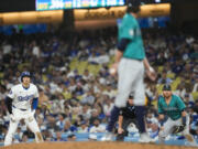 Los Angeles Dodgers designated hitter Shohei Ohtani (17) leads off of first as Seattle Mariners starting pitcher Logan Gilbert, center, looks back to first baseman Justin Turner, right, during the fifth inning of a baseball game in Los Angeles, Wednesday, Aug. 21, 2024.