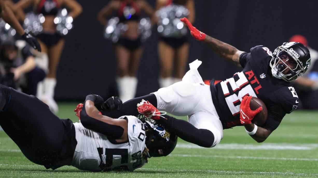 Jacksonville Jaguars defensive end Trevis Gipson (50) hits Atlanta Falcons running back Carlos Washington Jr. (28) in the first half of an NFL preseason footballl game, Friday, Aug. 23, 2024, in Atlanta.