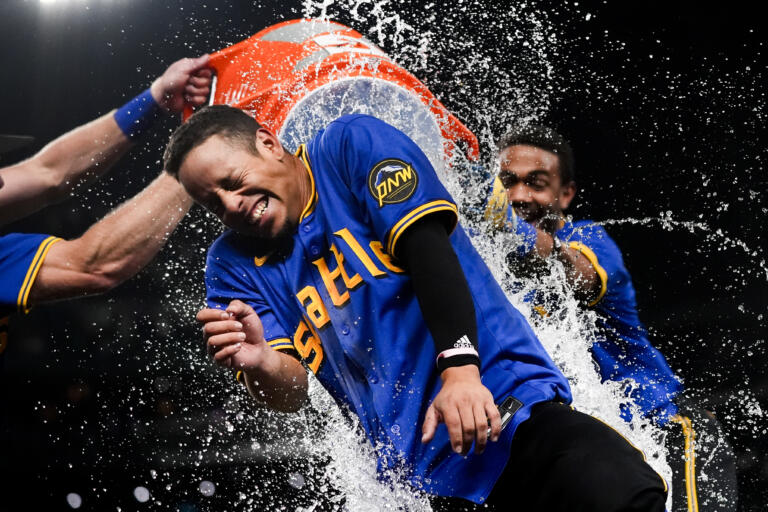 Seattle Mariners' Leo Rivas reacts to being doused by teammates, including Julio Rodríguez, right, after hitting a game-winning single against the San Francisco Giants in the 10th inning of a baseball game, Friday, Aug. 23, 2024, in Seattle. The Mariners won 6-5.