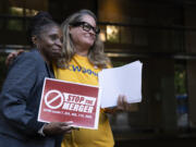 Faye Guenther, president of local UFCW 3000, hugs Carol McMillian, bakery manager at Kroger-owned King Soopers and member of Local 7, after a news conference about the Kroger and Albertsons merger outside the federal courthouse on Monday, Aug. 26, 2024, in Portland, Ore.