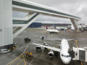 FILE - Planes taxi under the aerial passenger walkway at Seattle-Tacoma International Airport, March 3, 2022, in Seattle.