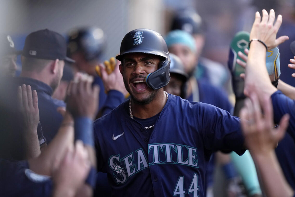 Seattle Mariners center fielder Julio Rodriguez is congratulated by teammates in the dugout after scoring on a fielding error during the first inning of a baseball game against the Los Angeles Angels Friday, Aug. 30, 2024, in Anaheim, Calif. (AP Photo/Mark J.