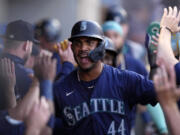 Seattle Mariners center fielder Julio Rodriguez is congratulated by teammates in the dugout after scoring on a fielding error during the first inning of a baseball game against the Los Angeles Angels Friday, Aug. 30, 2024, in Anaheim, Calif. (AP Photo/Mark J.