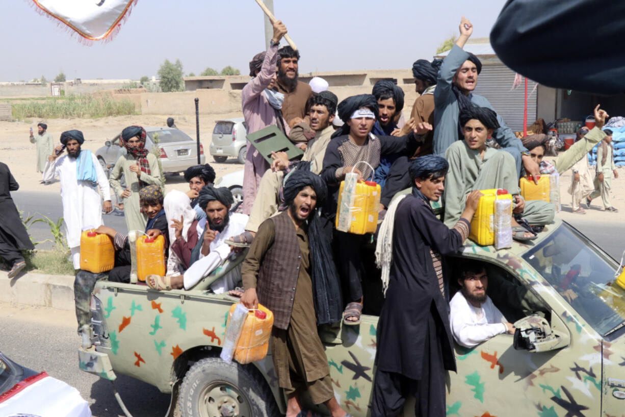 Taliban fighters carry dummy yellow canisters intended to represent homemade explosives, as they celebrate the third anniversary of the withdrawal of US-led troops from Afghanistan, in Lashkar Gah, Helmand province, southwestern Afghanistan, Wednesday, Aug. 14, 2024.