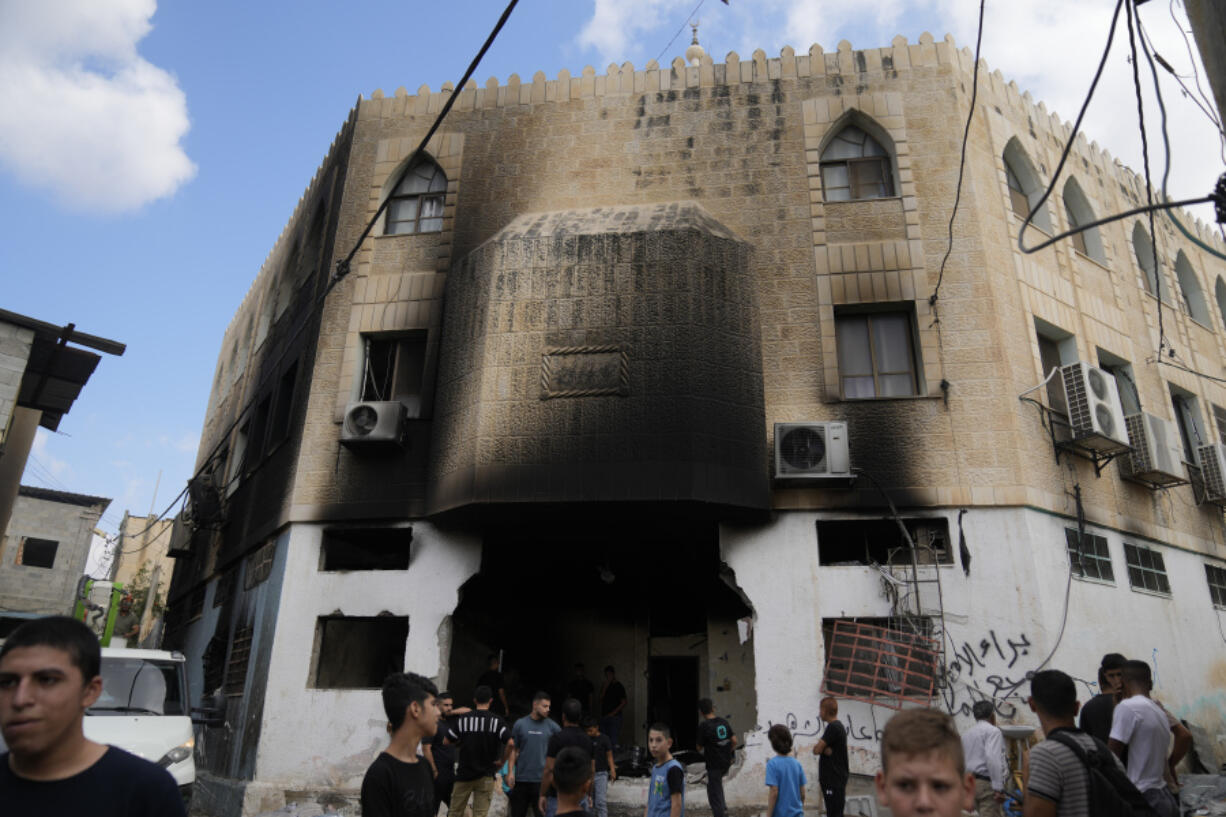 Palestinians stand outside a heavily damaged mosque following an Israeli military operation in the West Bank refugee camp of Al-Faraa, Thursday, Aug. 29, 2024.