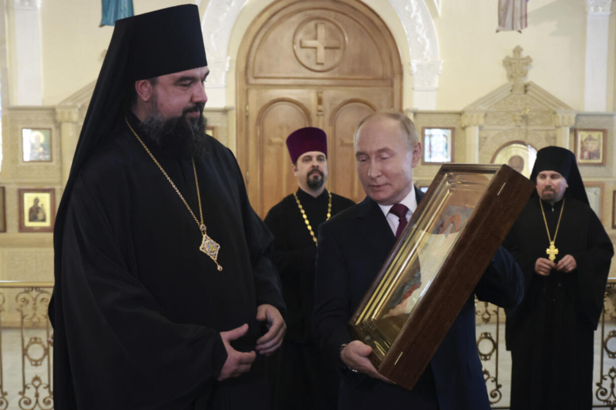 Russian President Vladimir Putin, second right, holds an icon during a visit to the Orthodox Holy Myrrhbearers Cathedral in Baku, Azerbaijan, Monday, Aug. 19, 2024.