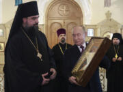 Russian President Vladimir Putin, second right, holds an icon during a visit to the Orthodox Holy Myrrhbearers Cathedral in Baku, Azerbaijan, Monday, Aug. 19, 2024.