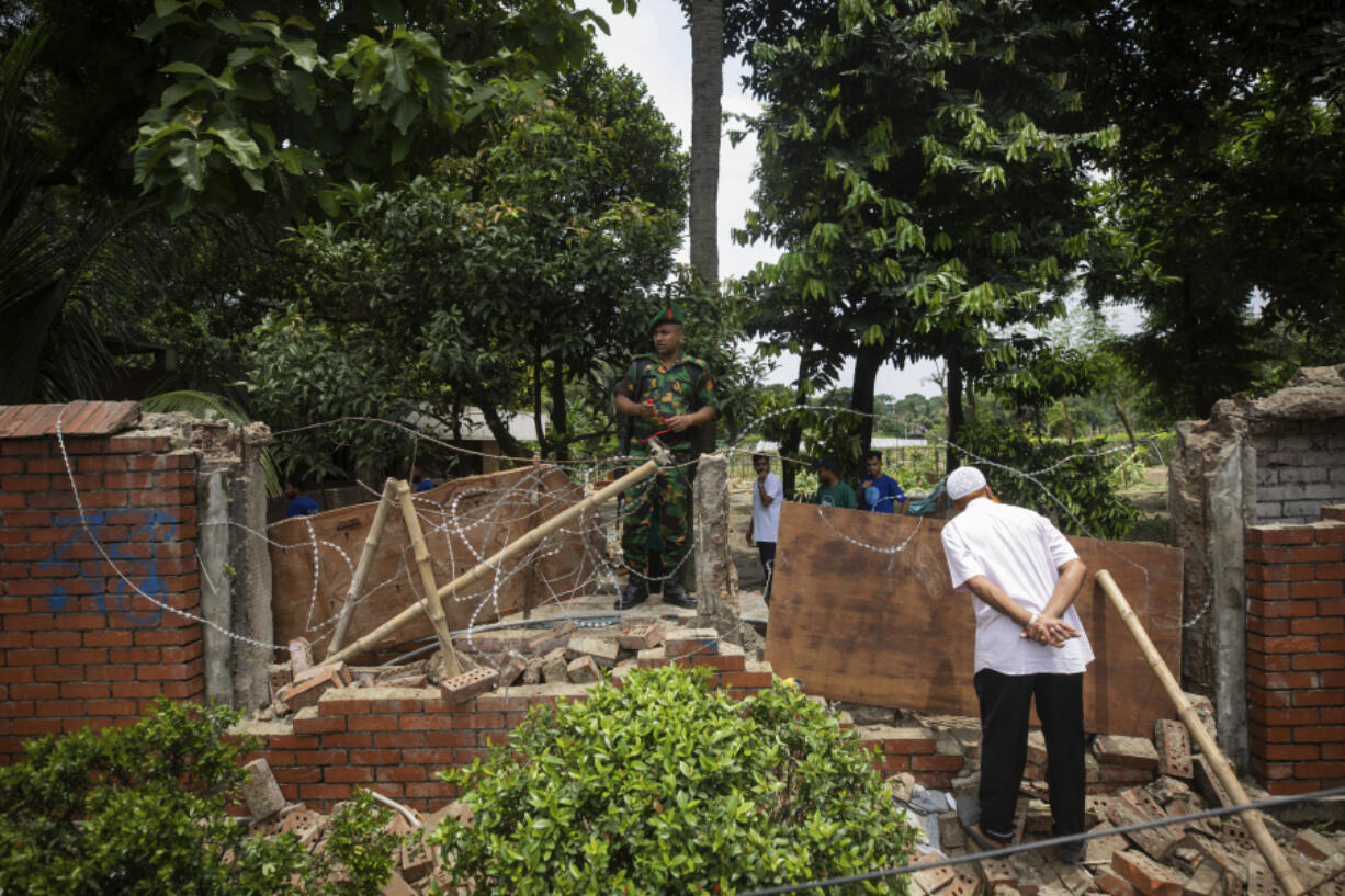 A man peeks inside the boundary wall of the vandalised house of Sheikh Hasina, who resigned as Prime Minister on Monday, in Dhaka, Bangladesh, Tuesday, Aug. 6, 2024.