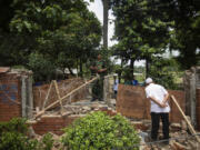 A man peeks inside the boundary wall of the vandalised house of Sheikh Hasina, who resigned as Prime Minister on Monday, in Dhaka, Bangladesh, Tuesday, Aug. 6, 2024.