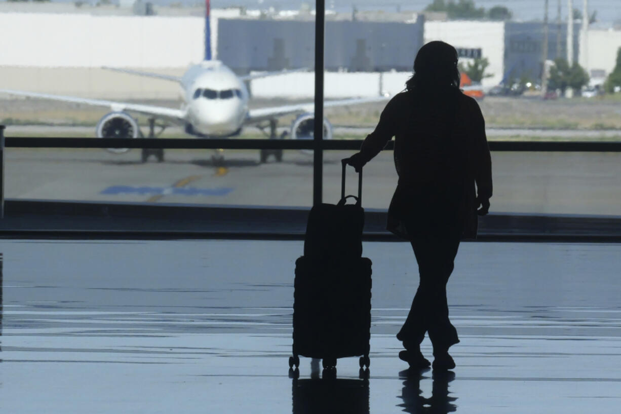 FILE - A holiday traveler looks out at a airplane at Salt Lake City International Airport, in Salt Lake City, July 3, 2024.