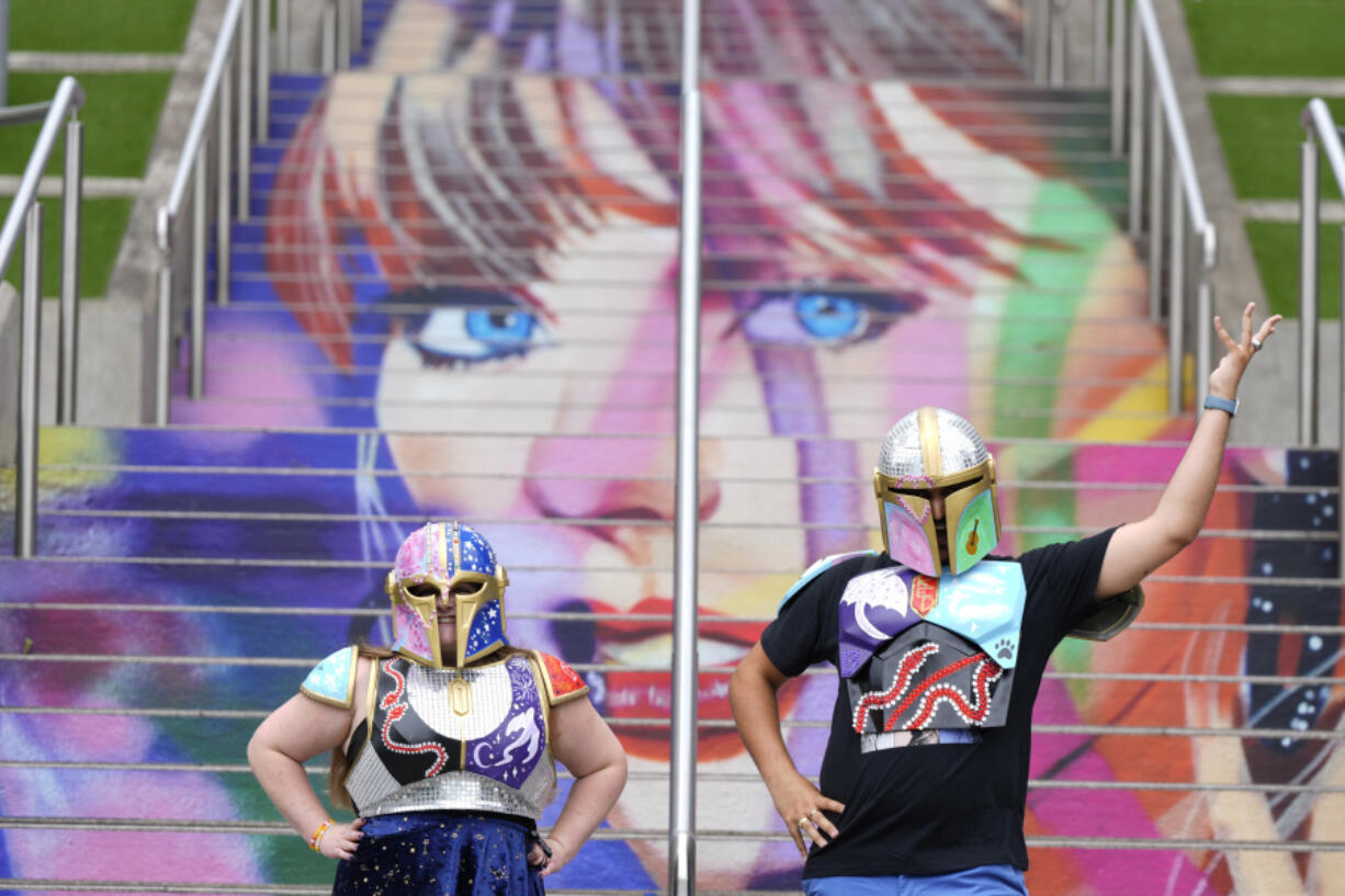 Kristina Broclebanl, left and Max Avatar Barnett who are Taylor Swift fans pose by a portrait of Swift painted on a stairway at Wembley Stadium in London, Wednesday, Aug. 14, 2024, ahead of a series of Taylor Swift concerts starting Thursday.