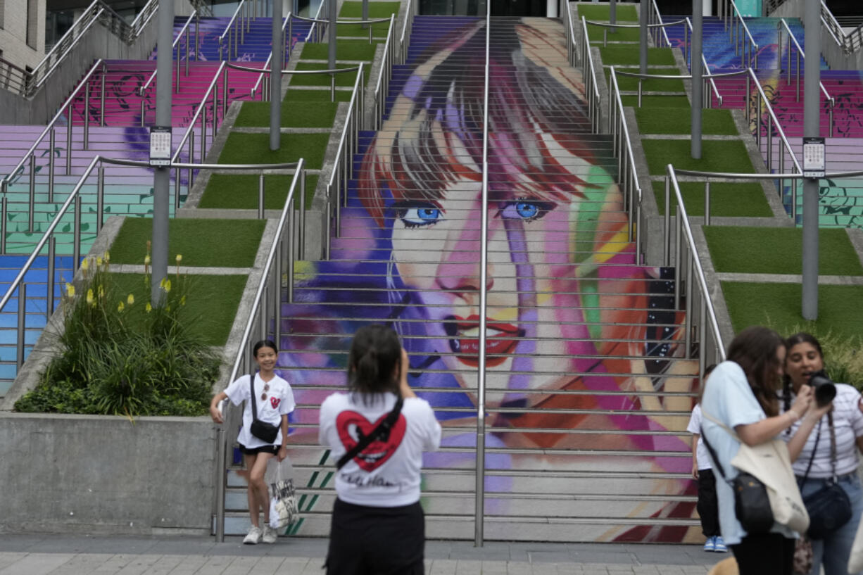 Fans pose by a Taylor Swift portrait painted on a stairway at Wembley Stadium in London, Wednesday, Aug. 14, 2024, ahead of a series of Taylor Swift concerts starting Thursday.