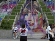 Fans pose by a Taylor Swift portrait painted on a stairway at Wembley Stadium in London, Wednesday, Aug. 14, 2024, ahead of a series of Taylor Swift concerts starting Thursday.